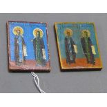 A near pair of Russian icons depicting two saints with gilt halos holding scriptures, painted wooden
