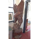 A large carved hardwood sculpture of an eagle fighting a tiger, H. 199cm