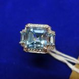 A ladies 18ct white gold and aquamrine ring, having inset asscher cut blue aquamarine flanked by two