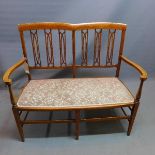 An Edwardian mahogany two seater settee, with boxwood inlay, raised on tapered legs, joined by