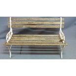 A two seat garden bench, with weathered teak slats, raised on white painted cast iron supports