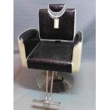 A Contemporary barber's chair, with black and white faux leather upholstery, raised on chrome base