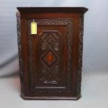 An 18th/19th century carved oak corner cabinet, with inlaid shell patera