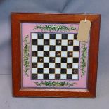 An early 20th century reverse painted glass chessboard, having oak frame, 48 x 48cm