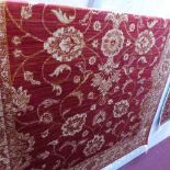A Zeigler style carpet with floral design on a red ground contained by beige ground border, 230 x