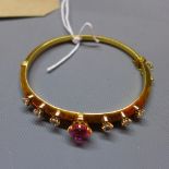 A yellow metal ladies bangle, inset with diamonds and central tourmaline.