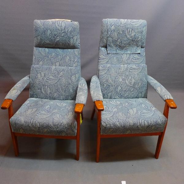 A pair of mid 20th century teak armchairs, with blue leaf pattern upholstery, raised on tapered legs