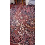 A Heriz carpet, with central geometric medallion on a rouge ground, contained by geometric border on