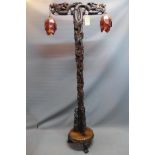 An early 20th century Chinese hardwood standard lamp, carved with flowers and dragons, raised on