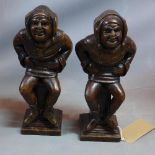 A pair of late 19th / early 20th century Continental carved oak Jesters, seated on a pedestal, on
