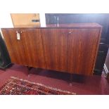 A late 20th century rosewood credenza, with four doors enclosing glass shelves, raised on square