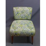 A mid 20th century oak cocktail chair, with floral upholstery, raised on tapered legs