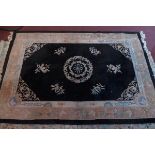 A mid 20th century Chinese woollen carpet, central floral medallion on a black ground within