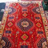 A Persian Qashqai carpet, having central geometric medallion on a red ground, contained within