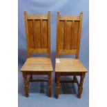 A pair of early 20th century oak hall chairs, raised on turned legs joined by a stretcher, (2)