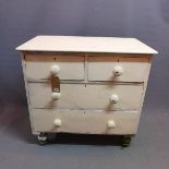 An early 20th century white painted pine chest, with two short over two long drawers, raised on