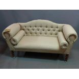 A Victorian style camel back sofa, with stone linen button back upholstery, raised on turned legs