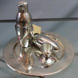 A silver plated cocktail shaker, in the form of a penguin, together with one other and two plates