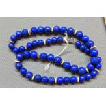 A lapis lazuli and white metal necklace, having lapis lazuli beads and white metal disks, the