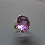 A 9ct yellow gold, amethyst and diamond set ring, the central oval cut amethyst within pave set