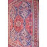 A Persian carpet with floral motifs, on a red ground, contained by borders, 317 x 227cm