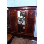 An Edwardian mahogany wardrobe, with central bevelled mirror plate, flanking two inlaid doors,