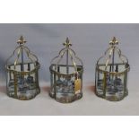 A set of three gilt metal wall hanging storm lanterns