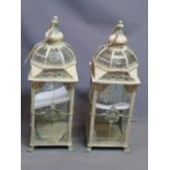 Two cream painted storm lanterns, raised on paw feet, H.73cm