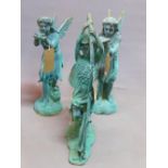 Three cast iron fairies in verdigris finish, one holding a bird, one a leaf, and the other leaning