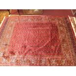 A Bokhara style carpet, with elephant pad motifs, on a red ground, contained by geometric borders,