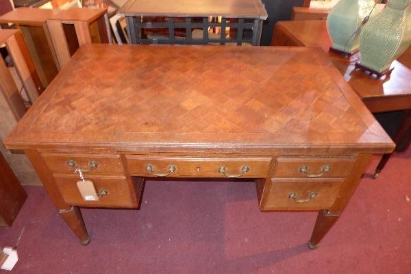 An early 20th century oak desk, with chequered top, five drawers, raised on tapered legs, H.78 W.135