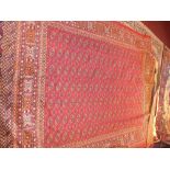A Bokhara style carpet, with elephant pad motifs, on a red ground, contained by geometric borders,