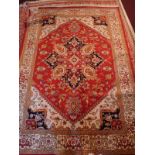 A Heriz style carpet, with central geometric medallion, on a red ground, contained by geometric