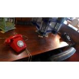 A vintage red telephone and a black reproduction version