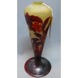 A slender Galle cameo vase with deep red hues on a warm yellow background. Flowers sprout from the