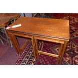 A mid 20th century Macintosh teak nest of three tables, with fold over top, raised on castors, H.