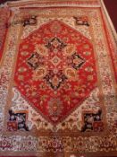 A Heriz style carpet, with central geometric medallion, on a red ground, contained by geometric