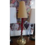 A table lamp with brass base and red velvet stem