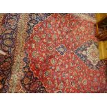 An Antique Kashan carpet, with central floral medallion, surrounded by floral motifs, on a red and