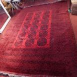 A large Afghan carpet, with elephant pad motifs, on a red and black ground, contained by repeating