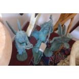 Three verdigris cast iron fairies; one holding a bird, one drinking from a leaf, and one holding a