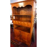A contemporary teak bookcase, with six drawers, two cupboard doors, raised on shaped base, H.190 W.