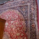 A Kashan style carpet, with central floral medallion, on a red ground, contained by floral