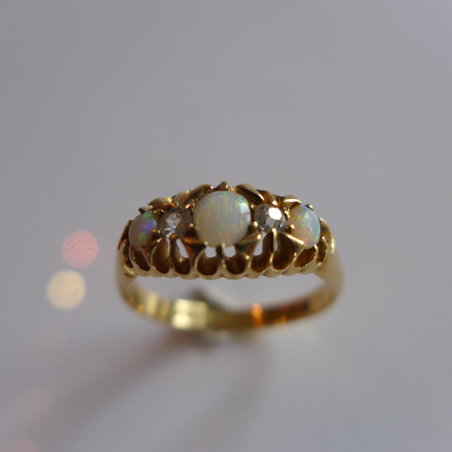 An 18ct yellow gold ladies ring inset with three opals and two diamonds, hallmarked Birmingham, L&L,