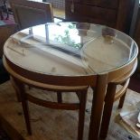 A mid 20th century teak circular nest of four tables, with glass top, by Nathan
