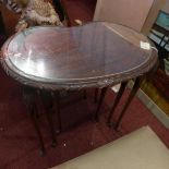 A nest of three 20th century kidney shaped side tables, with glass tops, with floral carved legs,