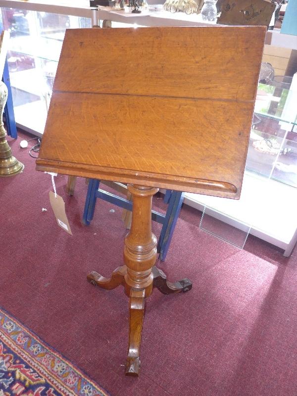 An oak music stand with adjustable top and tripod base