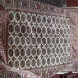A Bokhara style rug, with central elephant pad motifs, on a beige ground, contained by geometric