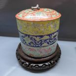 An early 20th century Chinese porcelain food carrier, in three sections, raised on hardwood stand