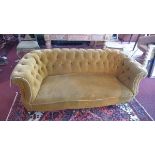 A Victorian Chesterfield sofa, with golden velour button back upholstery, raised on turned legs
